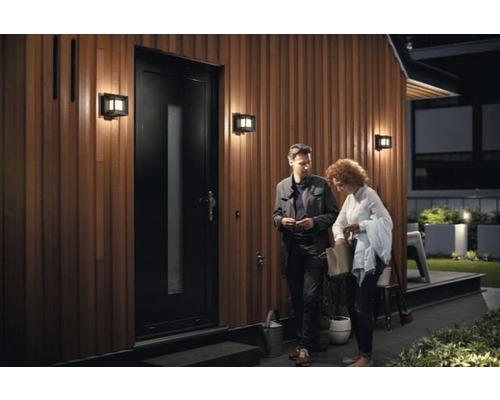 Façade de maison avec porte, éclairages extérieurs et deux personnes