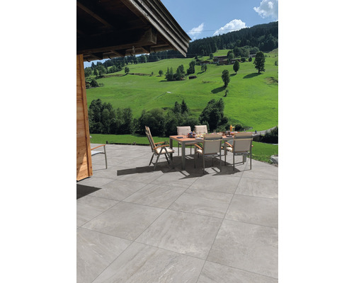 Terrasse mit Gartentisch und Stühlen vor einer grünen Landschaft.