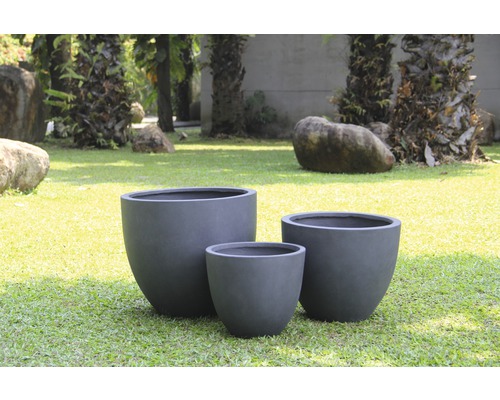 Drei Pflanzgefäße aus Faserzement in verschiedenen Größen im Garten.