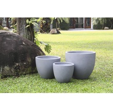 Drei graue Pflanzgefäße aus Faserzement auf einer Rasenfläche.