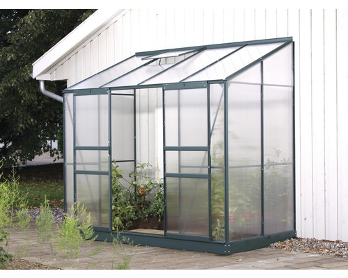 Gewächshaus mit Pflanzen vor einer Hauswand