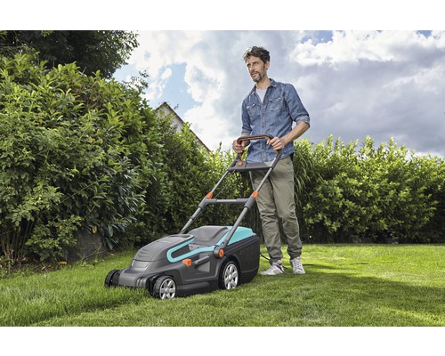 Mann mäht Rasen mit einem Gardena Rasenmäher im Garten.