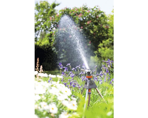 Kreisregner auf Stativ im Garten bewässert Blumen