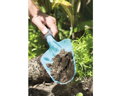 Une pelle à main avec de la terre dans le jardin.