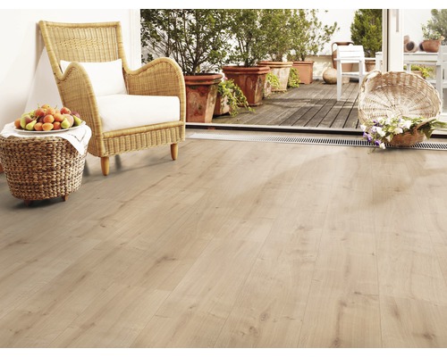 Pièce lumineuse avec sol stratifié, fauteuil en osier et corbeille de fruits