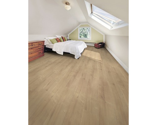 Chambre mansardée lumineuse avec sol stratifié, lit, commode et fenêtre de toit.