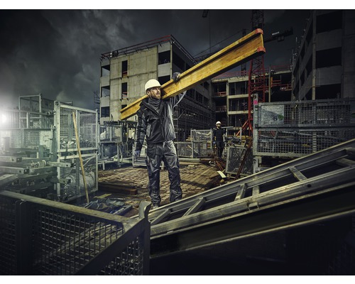 Ouvrier du bâtiment transportant une poutre en acier sur un chantier