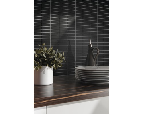 Scène de cuisine avec carreaux muraux noirs, plan de travail en bois, vaisselle et décoration