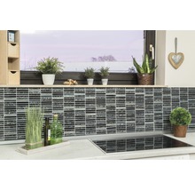 Küchenszene mit Mosaikfliesen an der Wand, Pflanzen und Küchenutensilien auf der Arbeitsfläche.