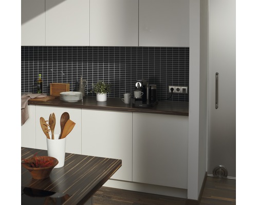 Cuisine claire avec plan de travail foncé, crédence foncée et accents de bois.