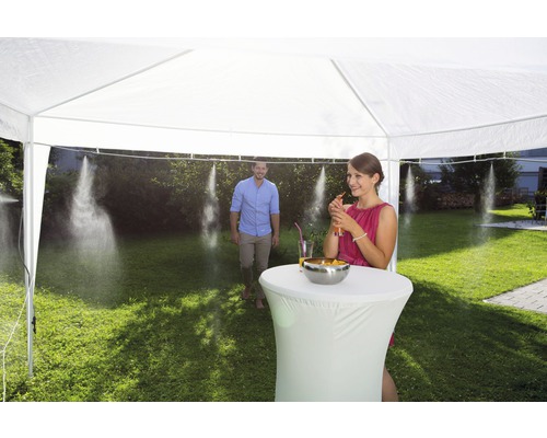 Szene mit Partyzelt und einer Person, die ein Getränk genießt, während eine Sprühvorrichtung für Kühlung sorgt