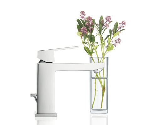 Glänzende Armatur neben einer Blumenvase.