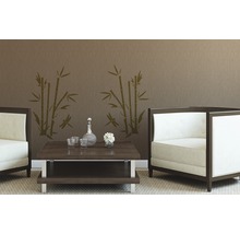 Salon avec deux fauteuils, table basse, carafe, verres, fleurs et sticker mural bambou