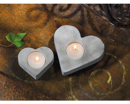 Deux bougeoirs en béton en forme de cœur sur fond rustique