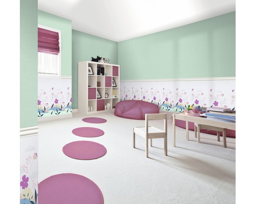 Helles Kinderzimmer mit weißen Möbeln, Wandbordüre und runden Teppichen