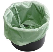 Grüner Bio-Müllbeutel in einem schwarzen Mülleimer