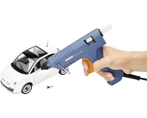 Pistolet à colle chaude dans la main devant une voiture jouet