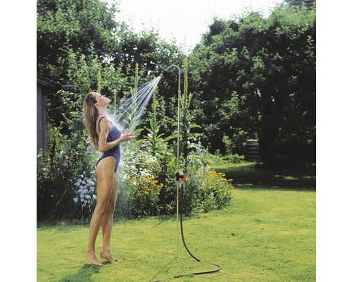 Frau unter einer Gartendusche im Garten.