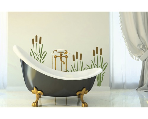 Freistehende Badewanne mit goldfarbenen Füßen vor Wand mit Pflanzenmotiv