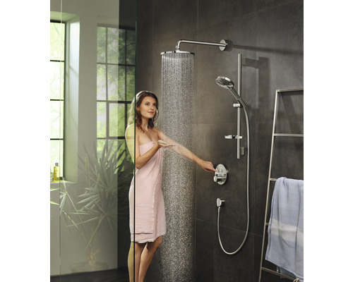 Femme sous un ensemble de douche avec douche de tête et douchette à main dans une salle de bain moderne