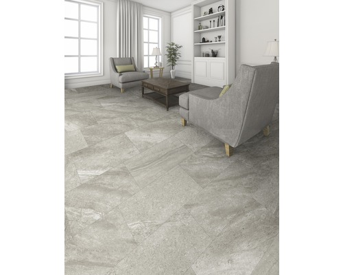 Salon avec carrelage gris, fauteuils et bibliothèque