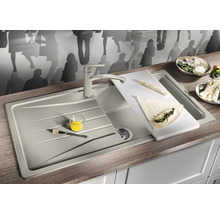 Évier de cuisine avec robinetterie, planche à découper et aliments sur un comptoir de cuisine.