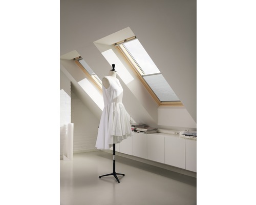 Chambre mansardée avec deux fenêtres de toit, armoire encastrée blanche et mannequin de couture avec robe blanche