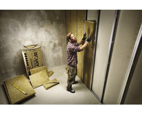 Homme installant de la laine d''isolation dans une pièce avec des murs en plaques de plâtre