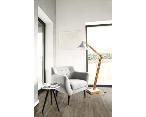 Heller Wohnraum mit Sessel, Stehlampe und Beistelltisch auf Bodenbelag