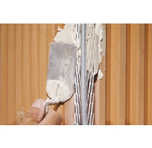 Auftragen von Mörtel auf eine Ziegelwand mit einem Spachtel