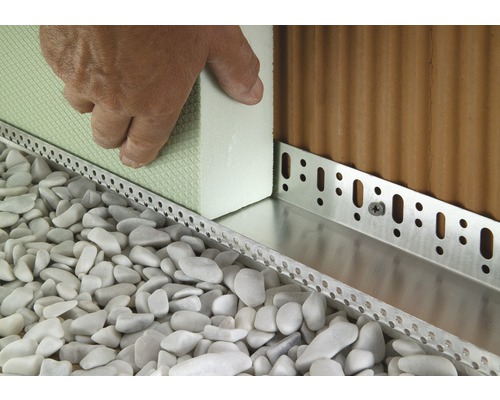 Gros plan sur les profilés d''enduit de soubassement et l''isolation thermique sur un mur de maison avec du gravier