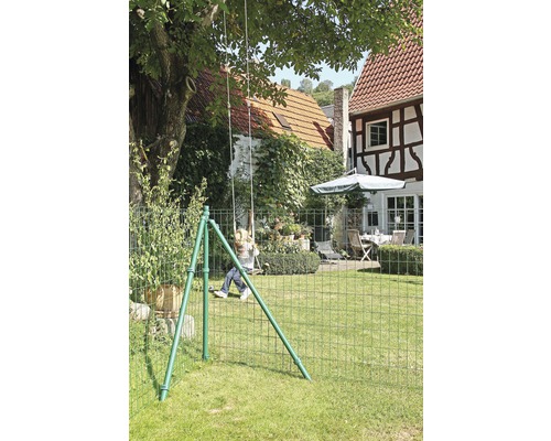 Gartenszene mit Kind auf Schaukel hinter einem Maschendrahtzaun.