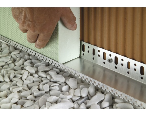 Vue détaillée d''éléments de façade en matériau isolant, fixés par des profilés de montage et entourés de graviers décoratifs.