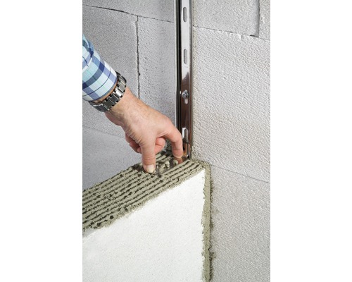 Person befestigt Dämmplatte mit Montageschiene an einer Wand