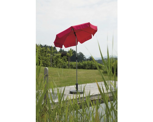 Parasol rouge sur une terrasse en bois avec une pelouse en arrière-plan.