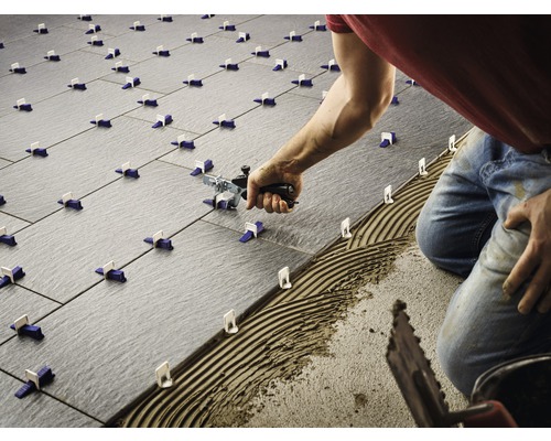 Carreleur posant des carreaux avec système de nivellement