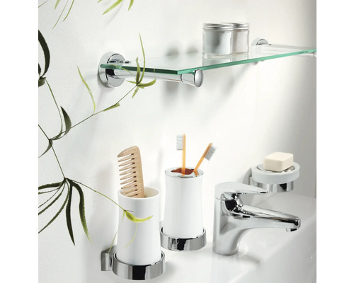 Scène de salle de bains avec étagère en verre, gobelet à brosses à dents avec brosses à dents, porte-savon, robinet et peigne