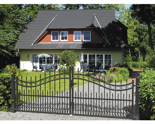 Schmiedeeisernes Gartentor vor einem Haus mit Gartenmöbeln