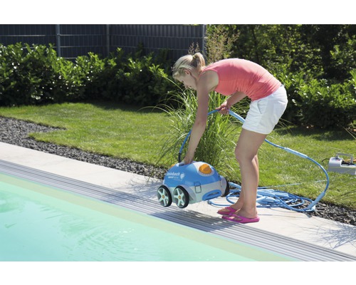 Une femme actionne un robot nettoyeur de piscine au bord de la piscine