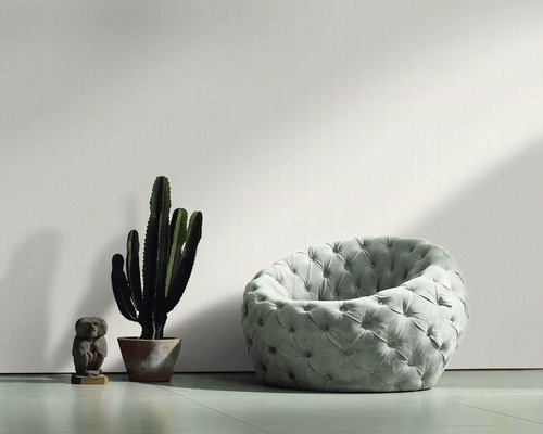 Intérieur décoratif avec fauteuil, cactus et figurine décorative devant un papier peint structuré