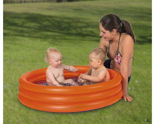 Pataugeoire gonflable avec deux enfants et une femme dans le jardin.