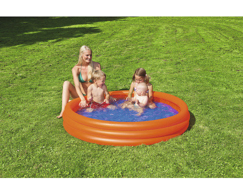 Pataugeoire gonflable avec des enfants qui jouent et une femme dans le jardin.