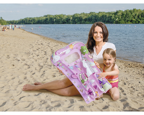 Frau und Kind am Strand mit einer aufblasbaren Luftmatratze mit Einhornmotiv.