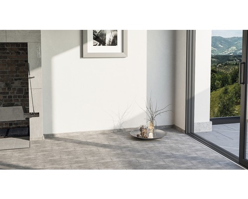 Pièce lumineuse avec carrelage gris au sol, barbecue et porte de terrasse