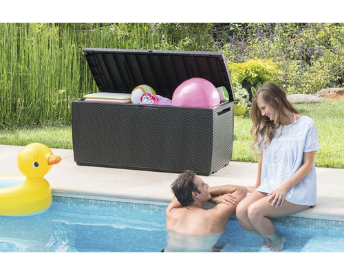 Geöffnete Gartenbox aus Kunststoff am Pool mit Badesachen gefüllt