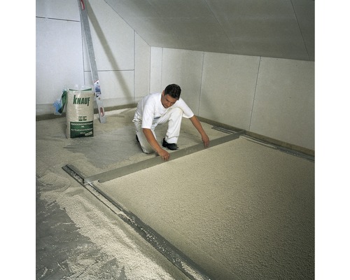 Mann gleicht Trockenschüttung mit einer Richtlatte aus