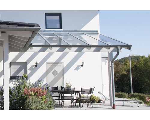 Terrasse avec toit en verre et mobilier de jardin près de la maison