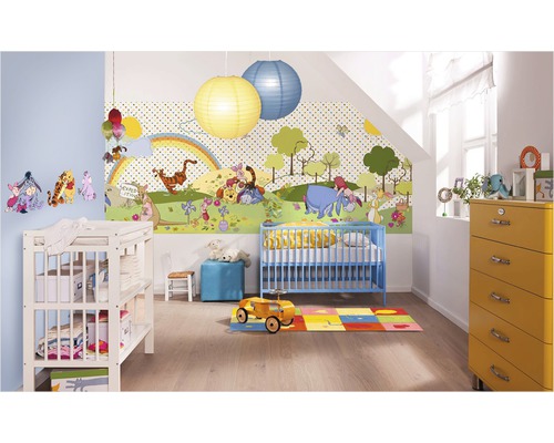 Ein Kinderzimmer mit einer Winnie Puuh Tapete, einem blauen Kinderbett, einer Wickelkommode und einer gelben Kommode.
