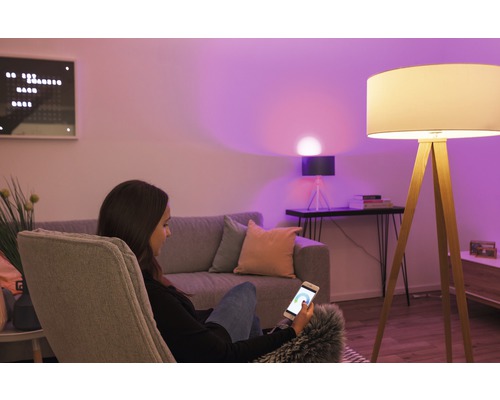 Salon avec lampe et femme utilisant un smartphone pour contrôler l''éclairage