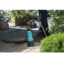 Garten-Schmutzwasserpumpe im Einsatz neben einem Kanaldeckel im Garten.
